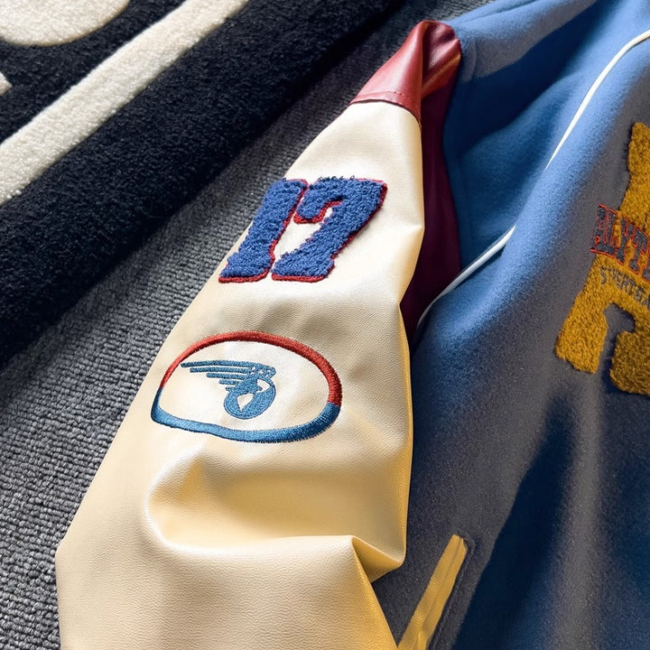 WT167 jacket in Blue shown in a close front view with sleeve embroidery and fabric details visible, on a gray fabric surface.