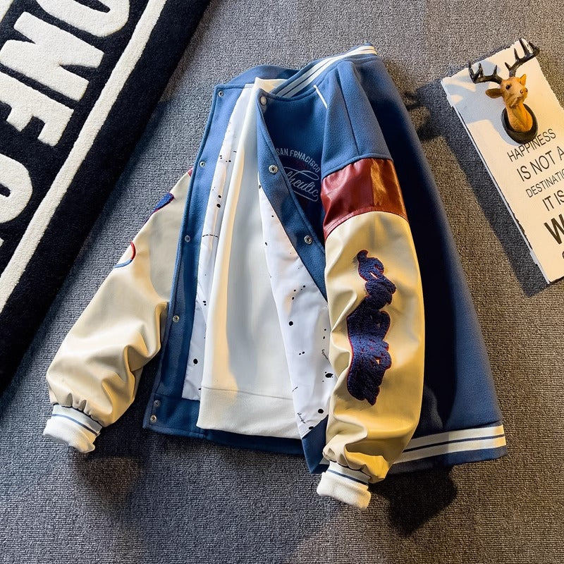 WT167 jacket in Blue shown in a front product view, showing contrast sleeves and embroidery, against a gray textile backdrop.