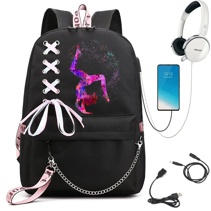 A black backpack with a bright seated gymnast print, light pink ribbon bow, pink webbing and chain, beside electronics props.