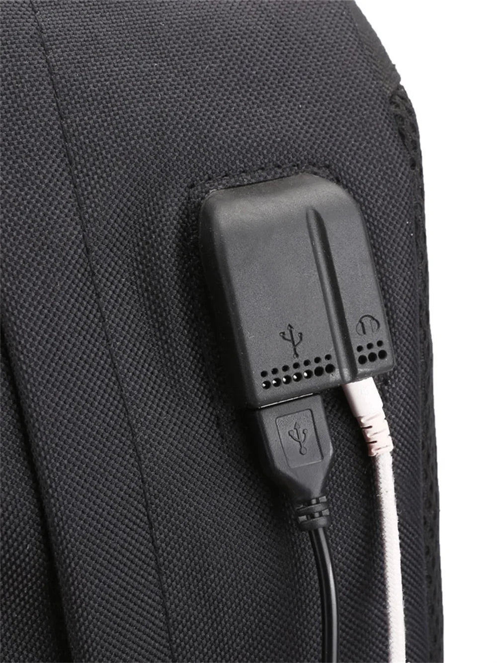 Detail view of the USB port on the side of the black canvas backpack, with a cable connected in the supplier reference photo.