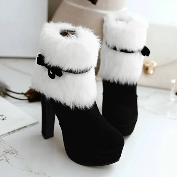 Black boots with white fluffy cuffs and matching bow straps, displayed upright in a pair with high heels and round toe shapes