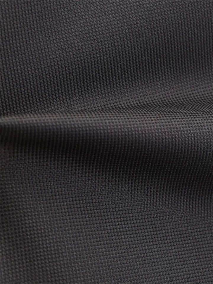Close view of the black outer fabric on the backpack, with the woven surface texture and a stitched horizontal seam up close.