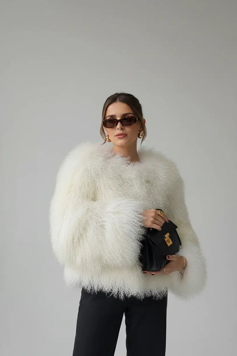 Shaggy faux fur jacket in white with cropped hem and oversized fit, held with a top-handle bag for polish

