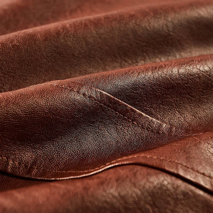 Close-up of the brown faux leather jacket surface showing its grain, sheen and panel seam.
