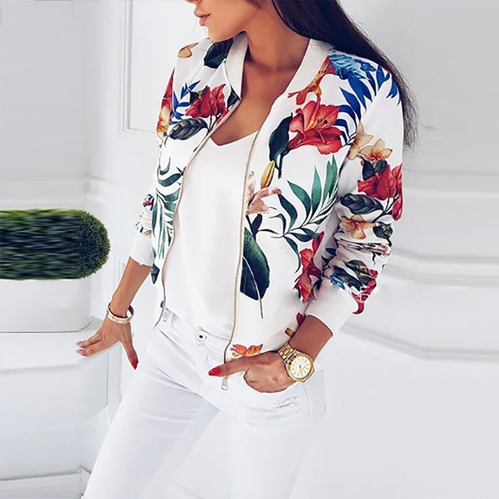 White floral bomber jacket worn open over a white top, showing the multicolor botanical print, ribbed cuffs and front zipper.