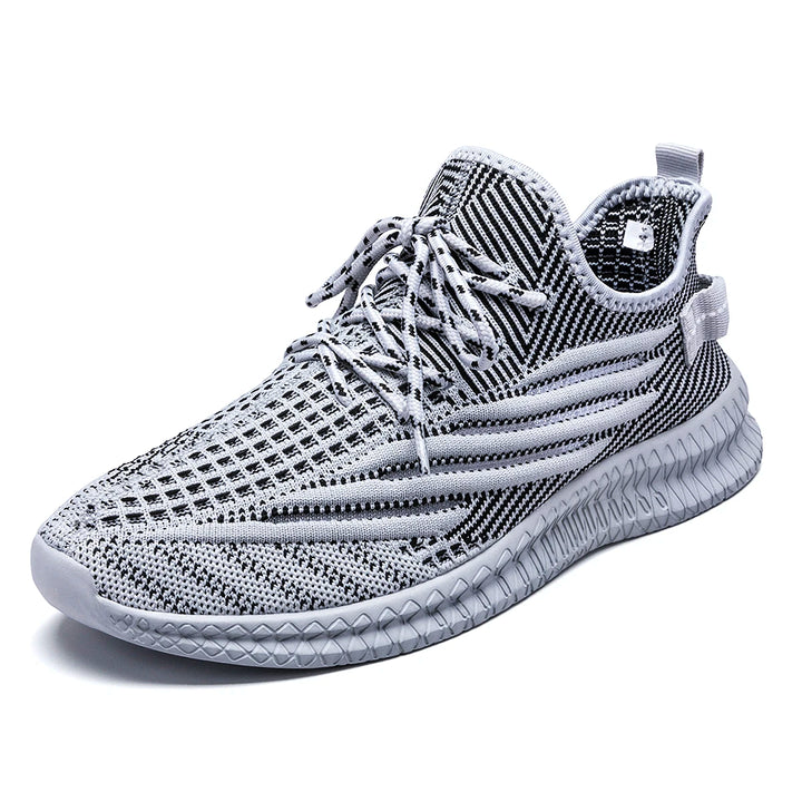 Gray mesh sneaker shown alone on white, with patterned knit, light laces and a ribbed sole shown in the source photograph.