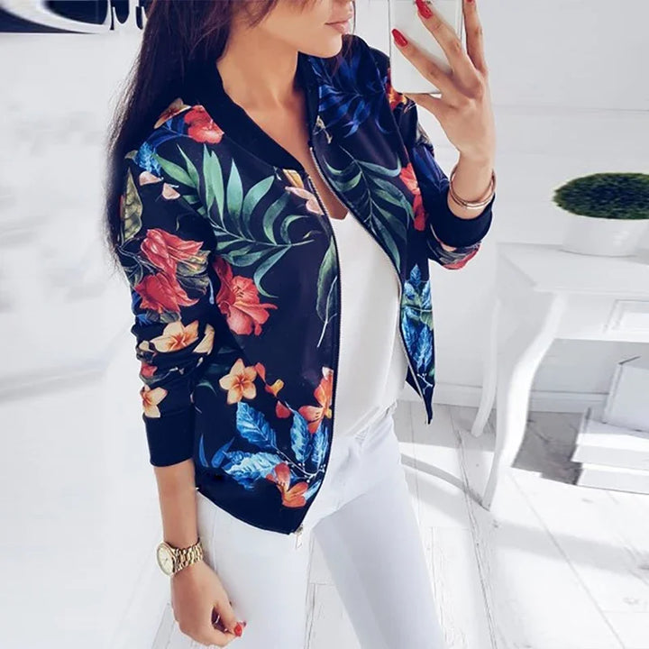 Dark Blue floral zip jacket worn open over a white top, showing colorful botanical print, long sleeves, and dark ribbed trim.