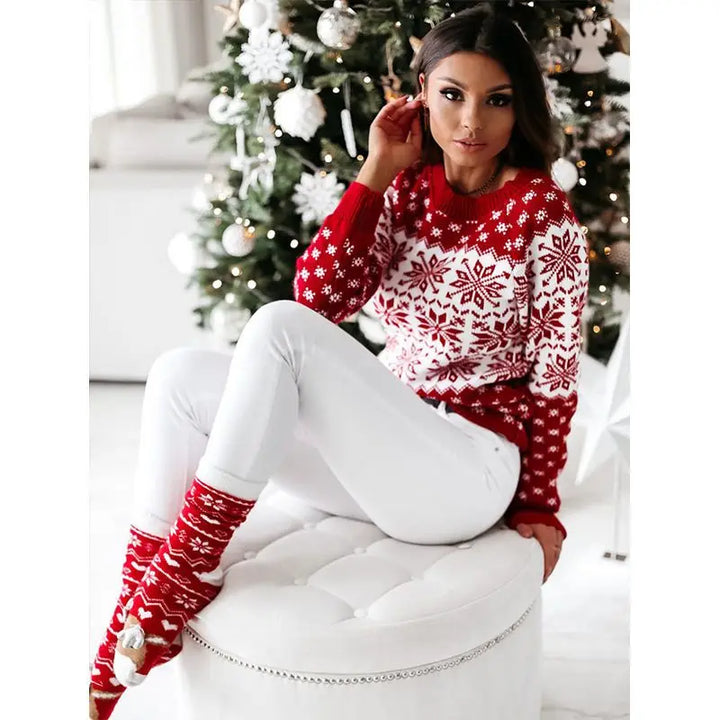 Red and white snowflake sweater with a red crew neck on a model beside a Christmas tree