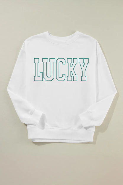 “Smiling woman in LUCKY graphic sweatshirt sitting on a bench with autumn leaves around”

