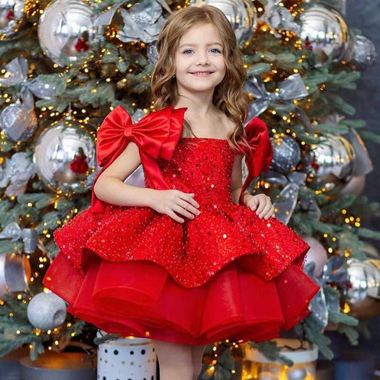 Twirling child in red Princess Dress under fairy-lights backdrop

