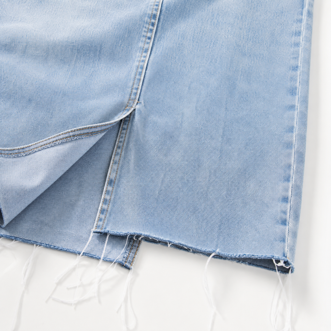 Close-up of light wash denim texture, stitching and raw hem detail