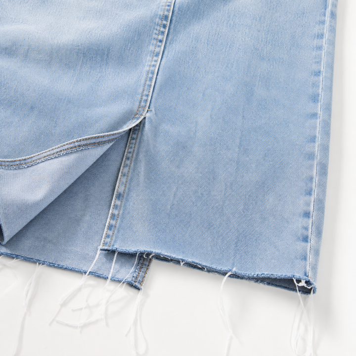 Close-up of light wash denim texture, stitching and raw hem detail