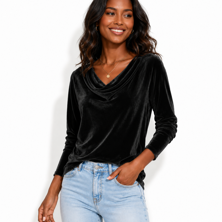 A woman wearing a black long-sleeve velvet cowl neck top and light wash blue jeans, standing against a plain white background.
