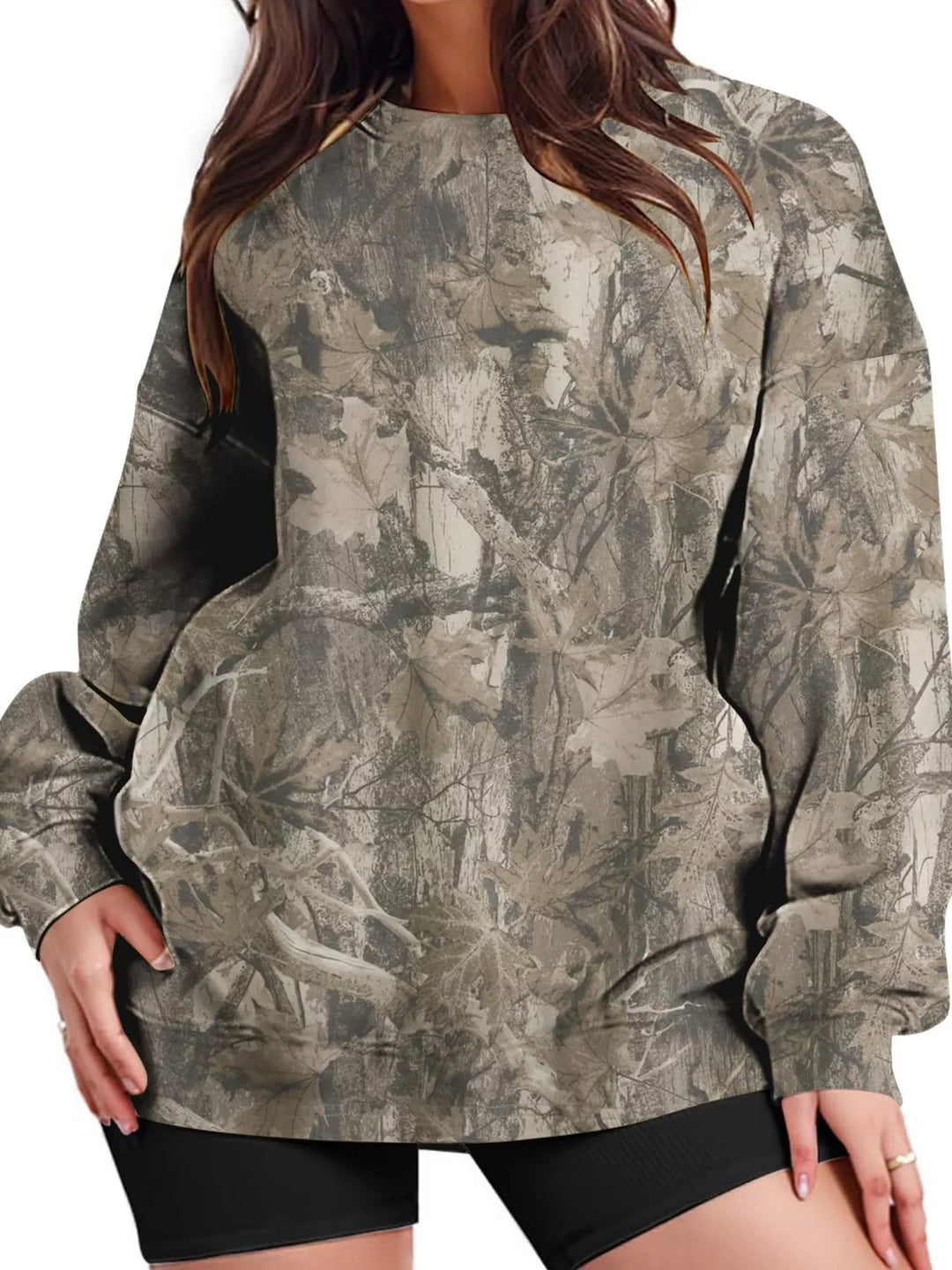 Woman in a light military green branch print sweatshirt shown from the front with long sleeves and a crew neck against white.