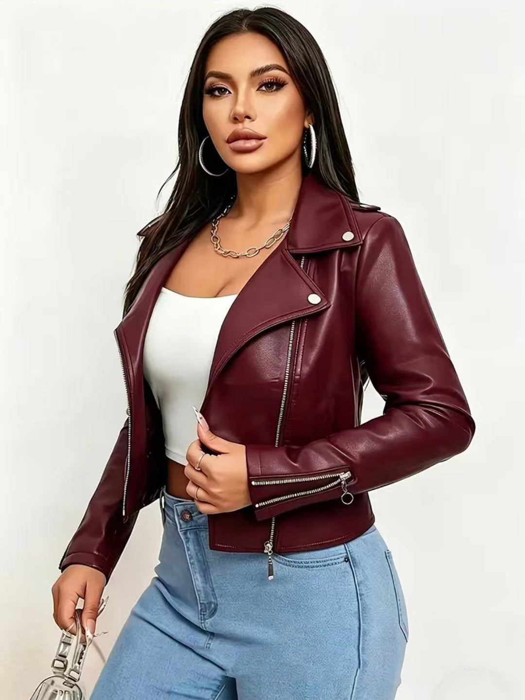Burgundy cropped moto jacket on a model in blue jeans, with silver lapel snaps, long sleeves and a diagonal front zip detail.