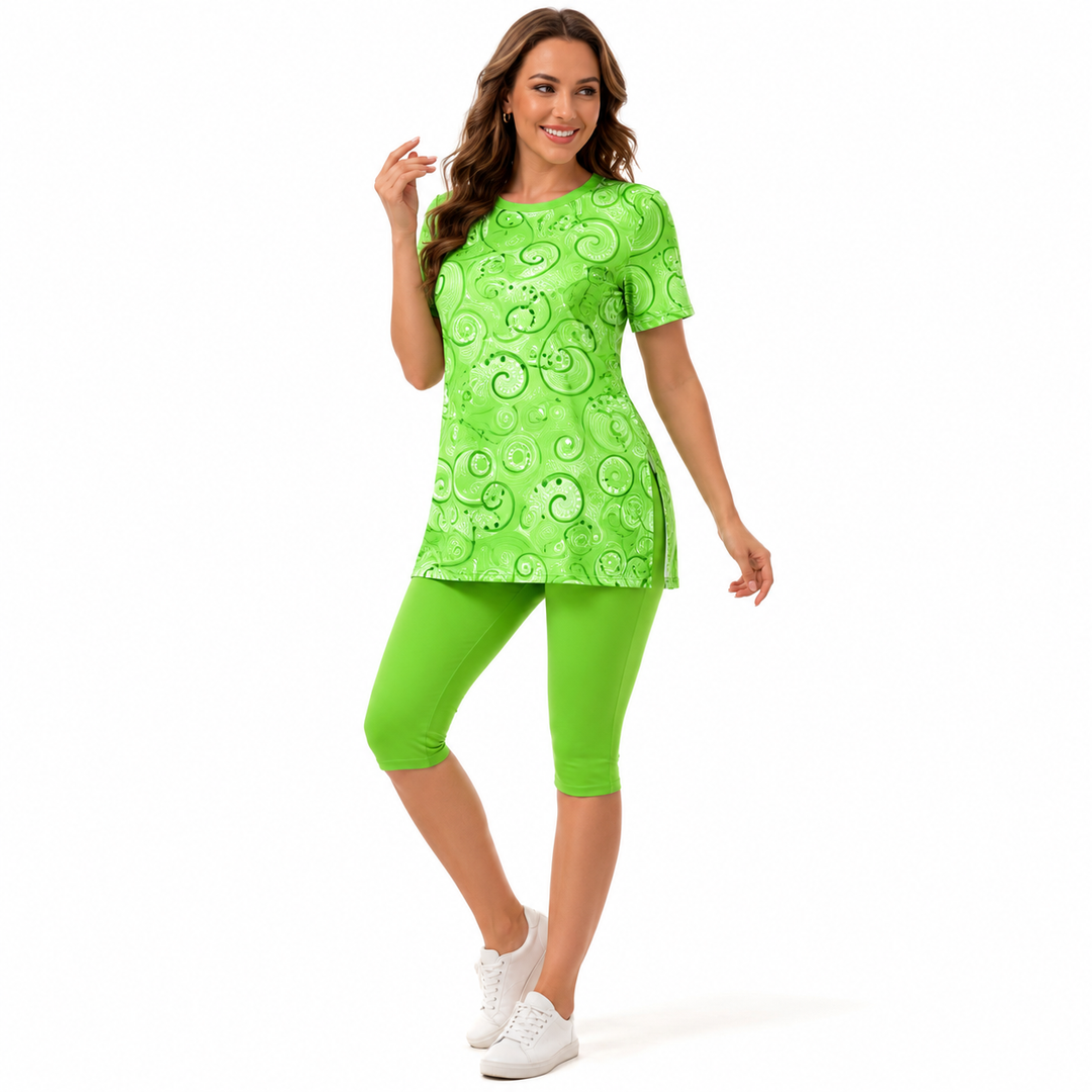 A woman modeling a bright lime green short-sleeve tunic top with a lighter green swirl pattern, paired with matching lime green capri leggings and white sneakers, against a plain white background.