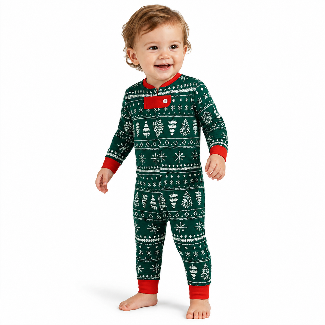 Smiling baby modeling green Christmas pajamas with white festive print and red trim on a white background.