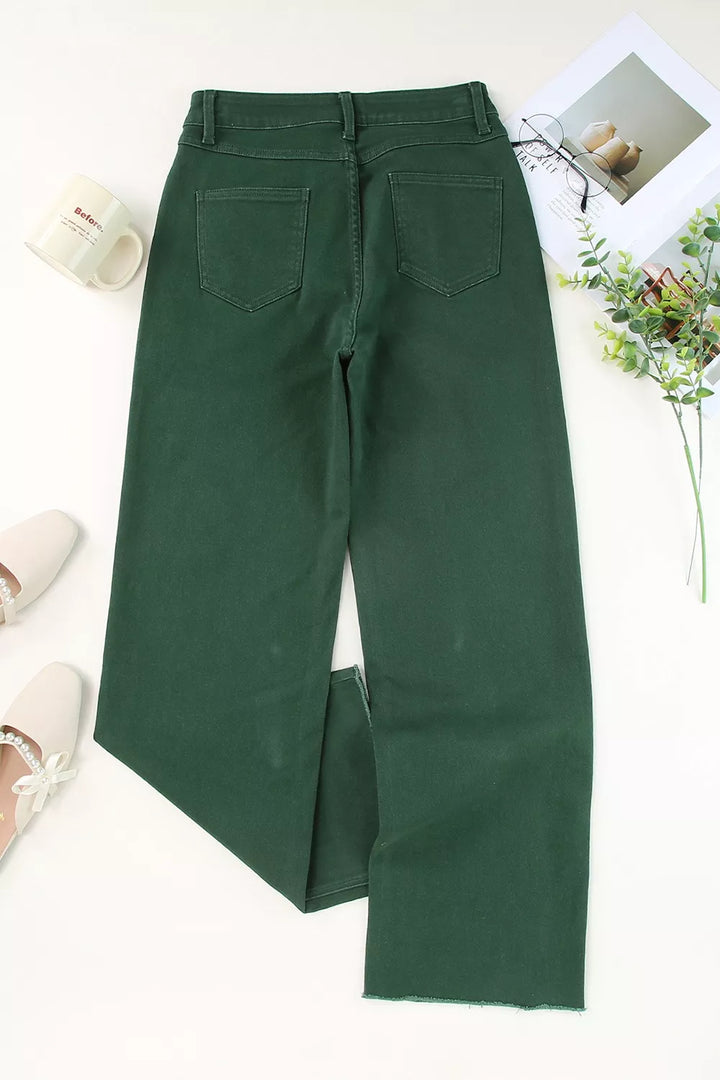 Flat lay of crossover waist raw hem jeans showing the waistband shape and full leg line