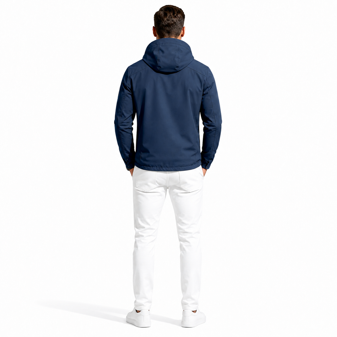 A man viewed from behind wearing a navy blue hooded jacket, white pants, and white sneakers against a plain white studio background.