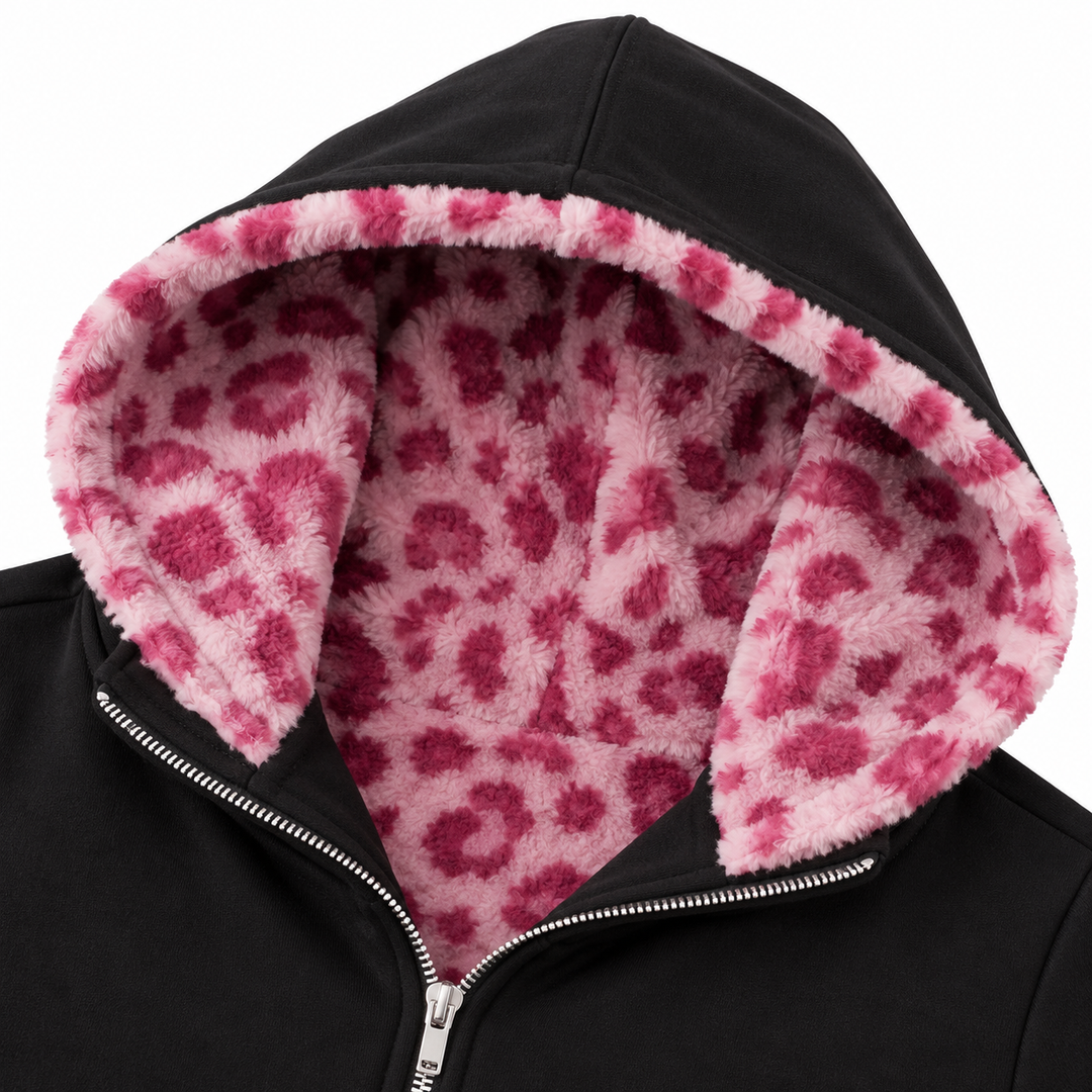 Close-up of the pink spotted hood lining, black outer fabric and silver zipper, showing the pattern and edging against white.