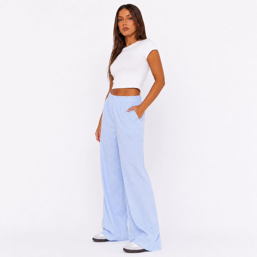 Blue striped wide leg pants for women on a studio model in three-quarter pose, highlighting elastic waist and fluid leg drape.