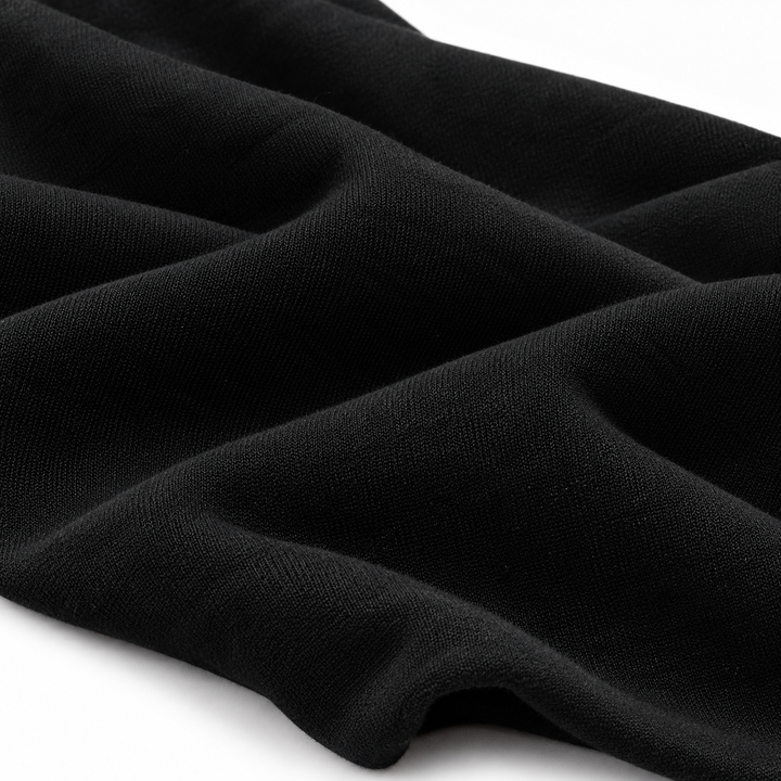 Close-up of black hoodie fabric arranged in soft folds, showing its visible surface texture against a clean white background.