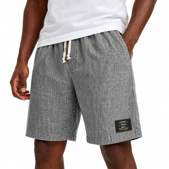 A person wearing heather gray drawstring shorts with a small black brand patch on the lower left leg, paired with a white t-shirt against a plain white background.