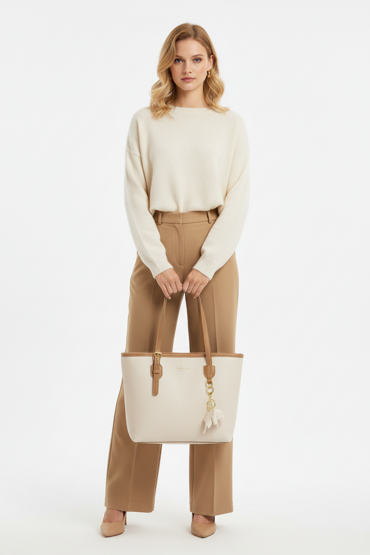 Woman holding a cream tote bag against a white background