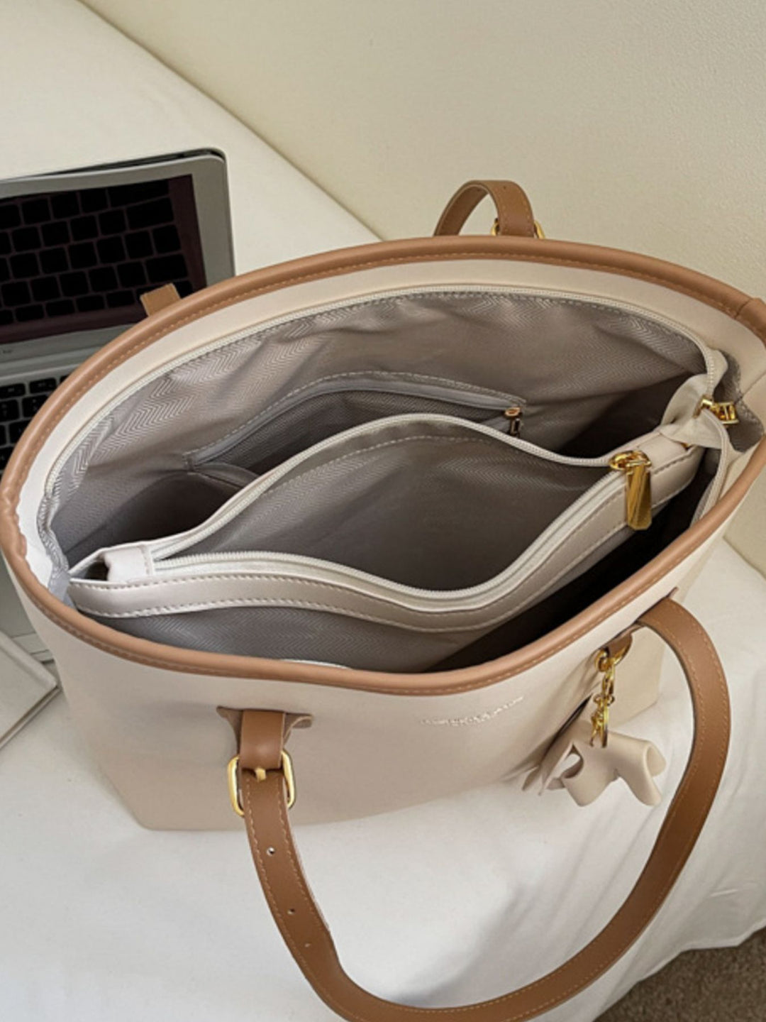 Beige handbag with brown handles and trim on a white surface.