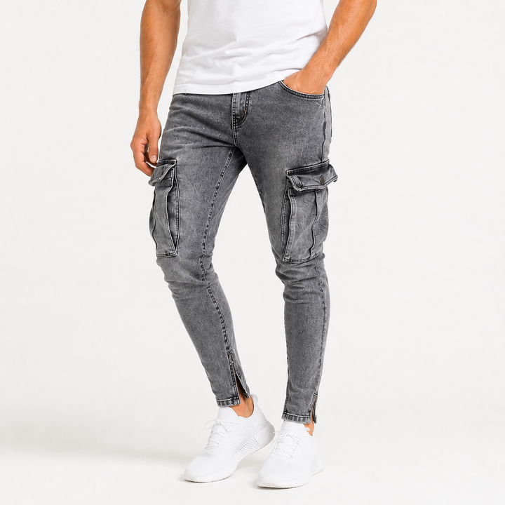 Close product view of washed gray cargo jeans for men showing denim texture, visible seams, tapered legs and large thigh cargo pockets.