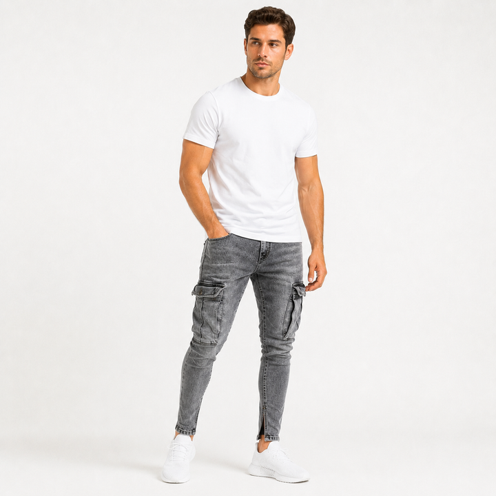 Commercial studio image of washed gray cargo jeans for men on an adult male model with tapered styling and large thigh cargo pockets.