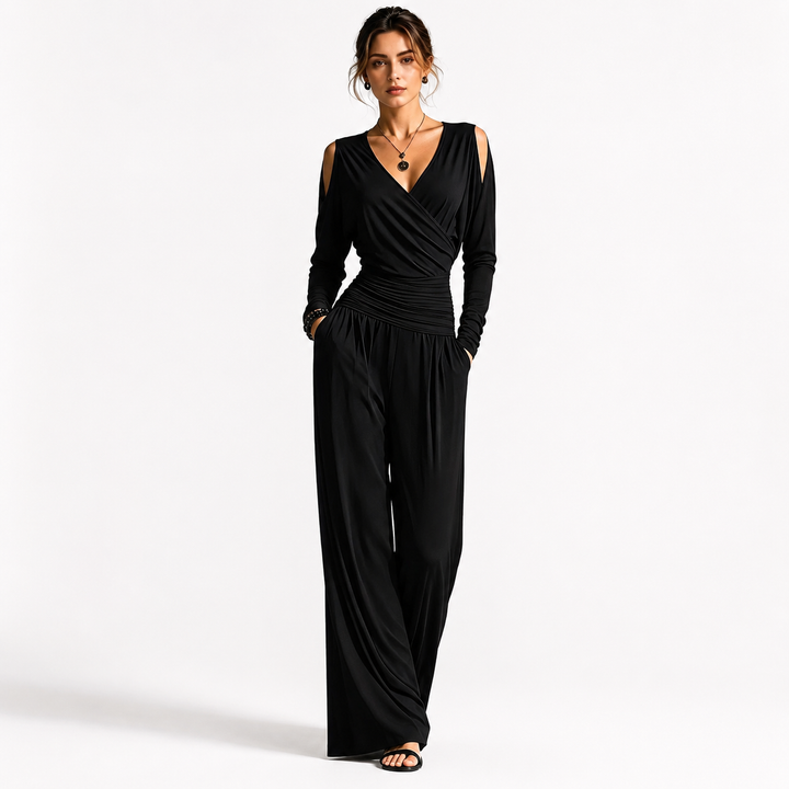 Black Milk Silk jumpsuit on a woman with visible face, V-neck wrap bodice, cold-shoulder sleeves, ruched waist and wide-leg pants.
