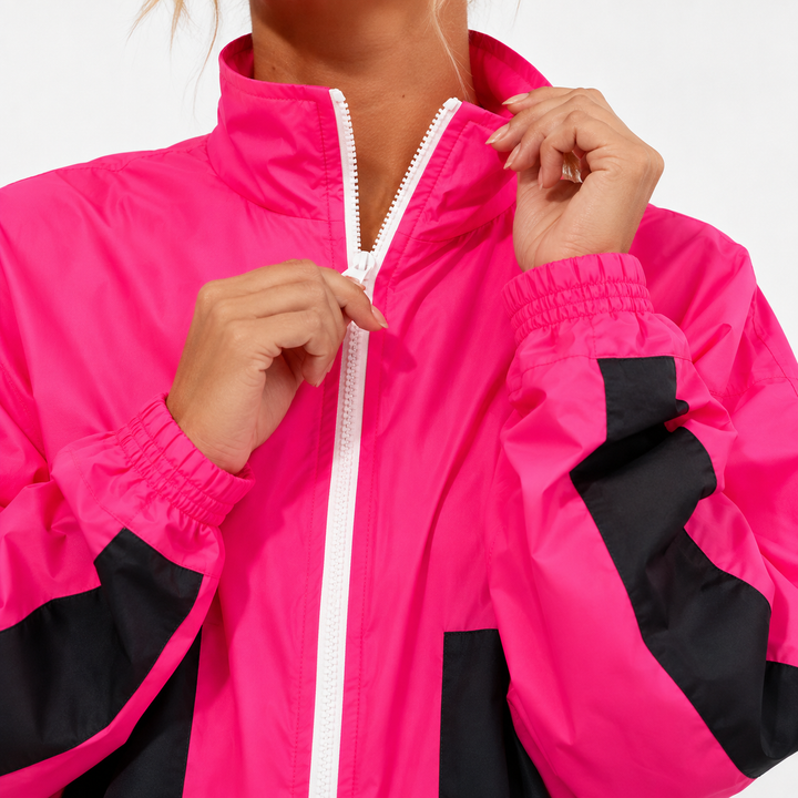 Close up of hot pink and black sports suit with white zipper, high collar and elastic cuff