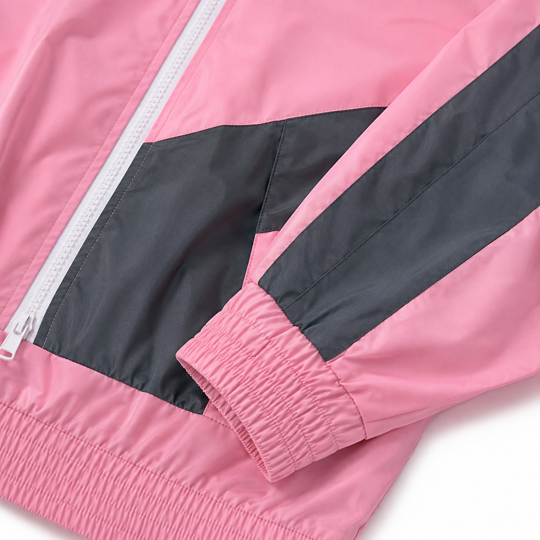 Close up of light pink and dark gray sports suit fabric, seams, zipper and elastic cuff