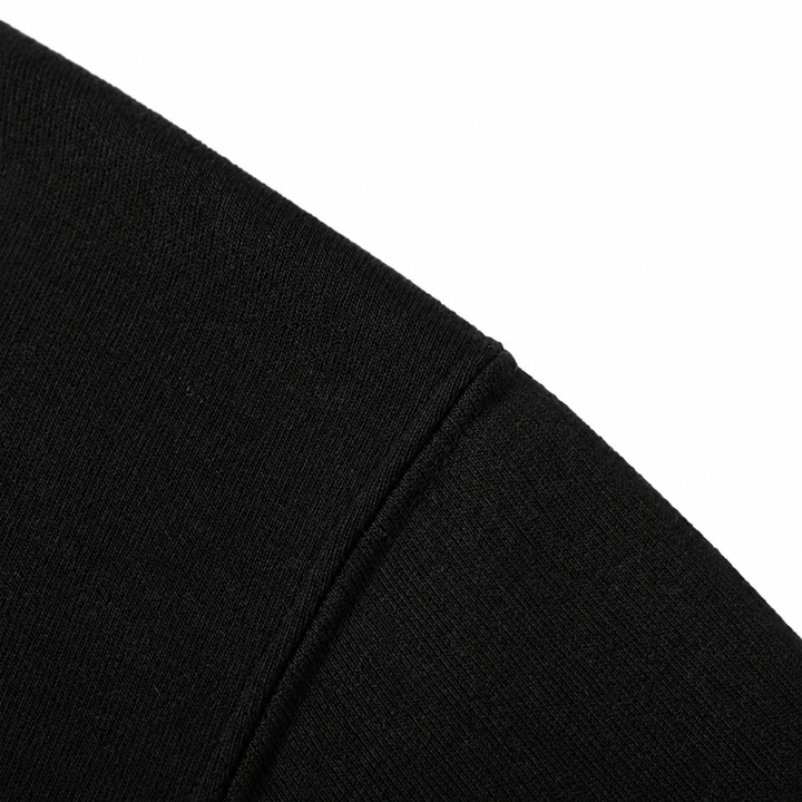 Close-up of black hoodie fabric and the shoulder seam on a white background.