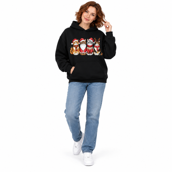 Full-length auburn-haired woman wearing a black festive cat-print hoodie and blue jeans.