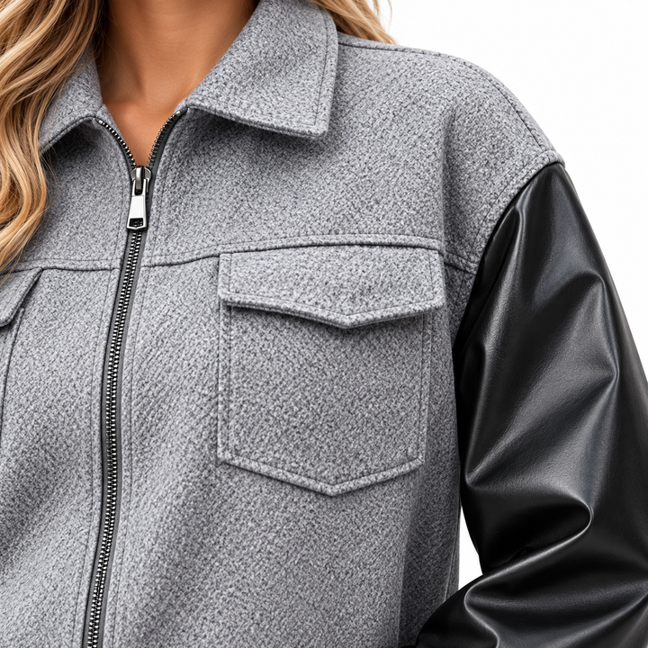 Close-up of gray textured jacket body, zipper, flap pocket and black sleeve