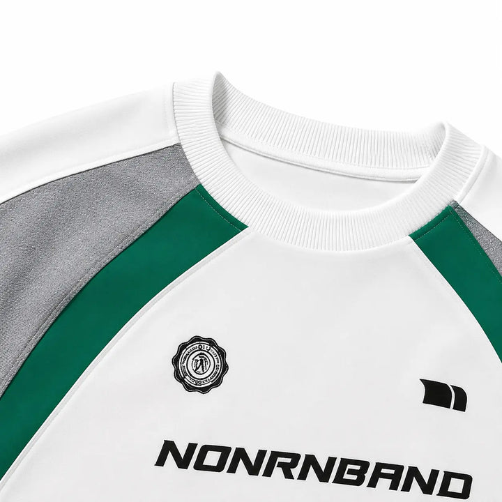 Close-up of ribbed collar, gray raglan shoulder, green insert and chest details on White color block sweatshirt.