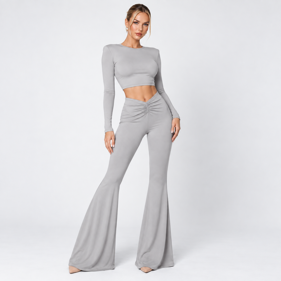 Gray crop top and pants set on model in studio light showing long sleeves, ruched front waist and flared trousers