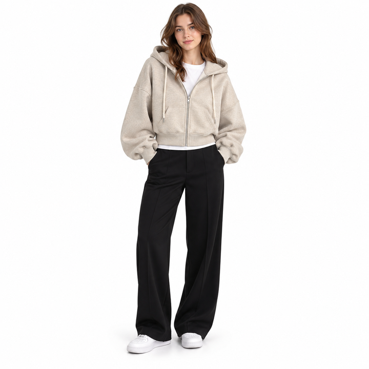 Photograph of cropped zip up hoodie in beige, front view, with the garment clearly visible, against a plain white background.