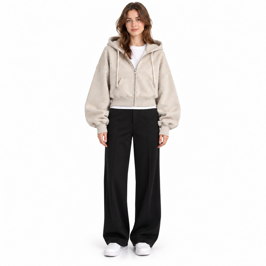 Photograph of cropped zip up hoodie in beige, straight front view, showing garment details, against a plain white background.