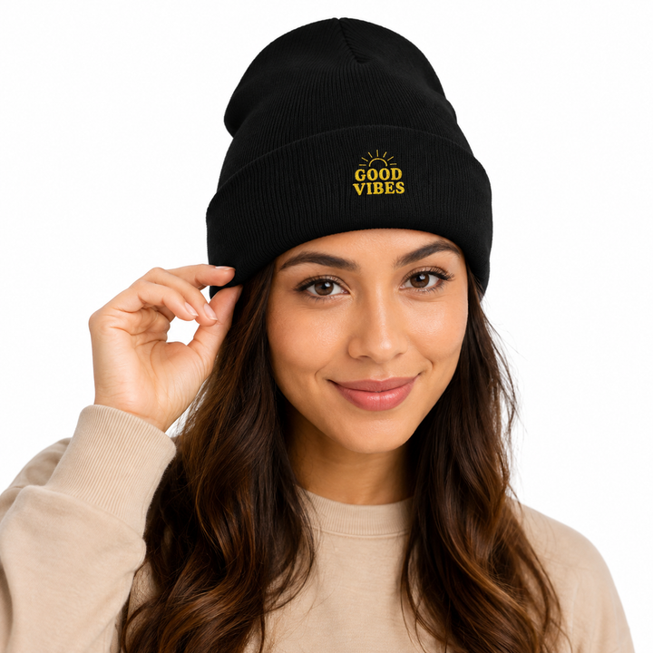 Close studio portrait of woman touching black cuffed beanie, highlighting Good Vibes embroidery and knit detail