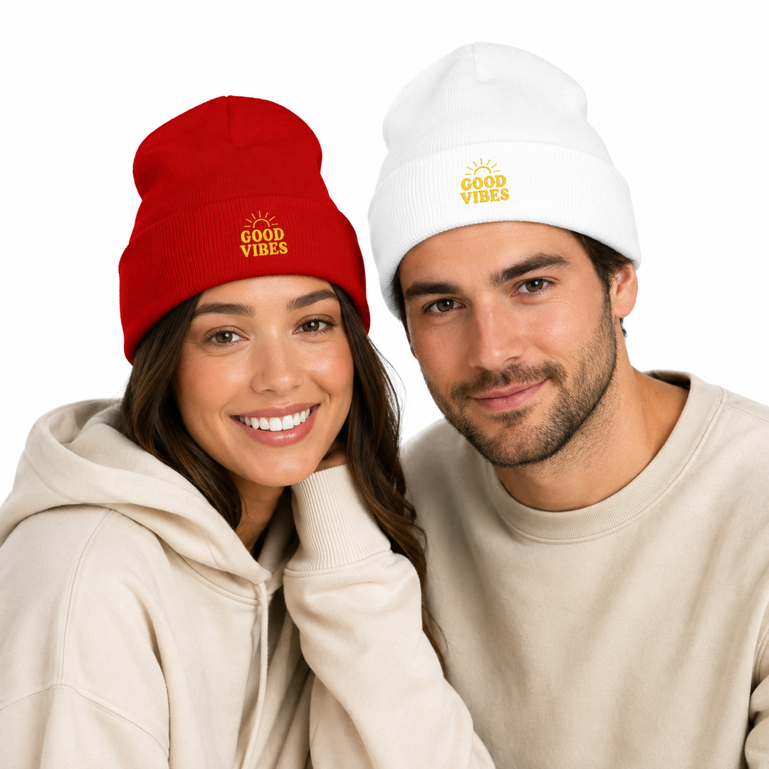 Woman wearing red cuffed beanie beside man wearing white cuffed beanie with matching Good Vibes embroidery