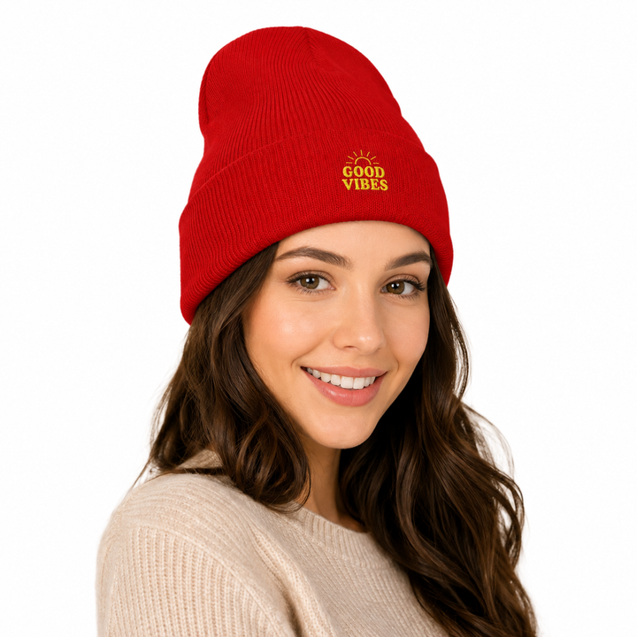 Woman wearing red cuffed beanie with embroidered Good Vibes design, shown in a polished white studio setting