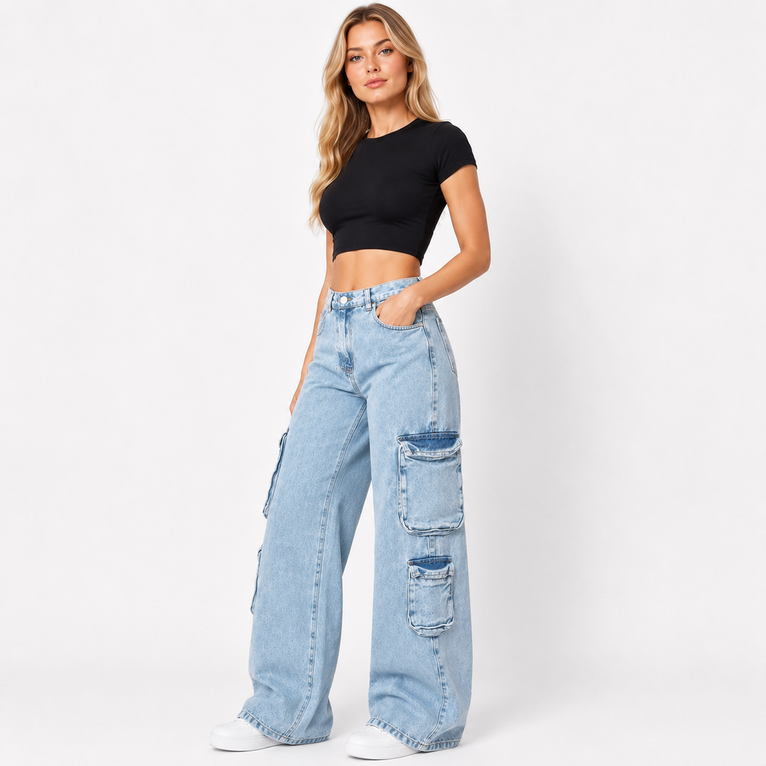 A woman modeling light-wash wide-leg cargo jeans with a black crop top and white sneakers, standing against a plain white studio background.