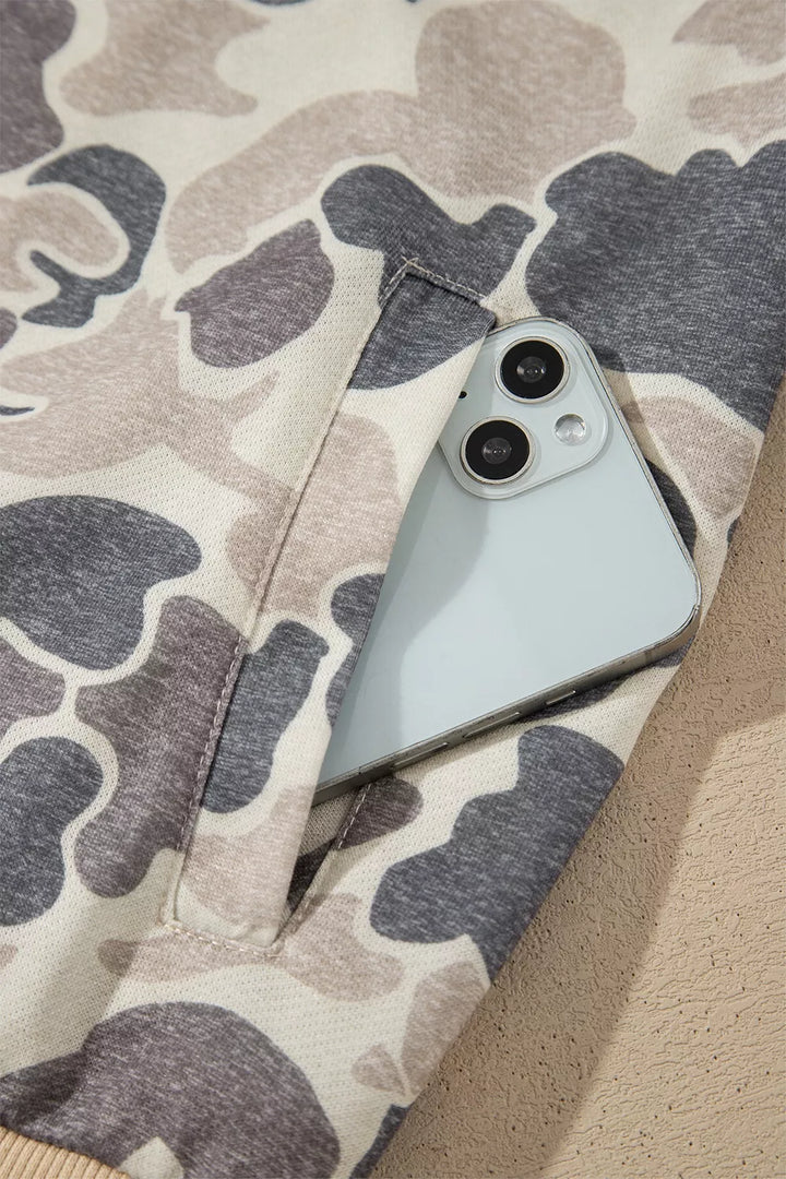 Close view of a front welt pocket holding a phone, with stitching visible against cream and charcoal camouflage print fabric.