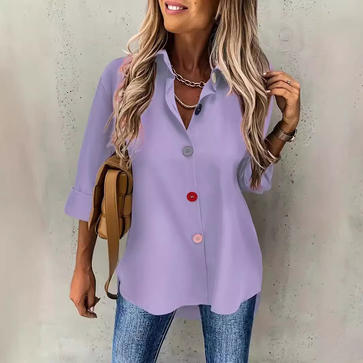 Woman wearing a light purple button-up shirt and blue jeans against a neutral background