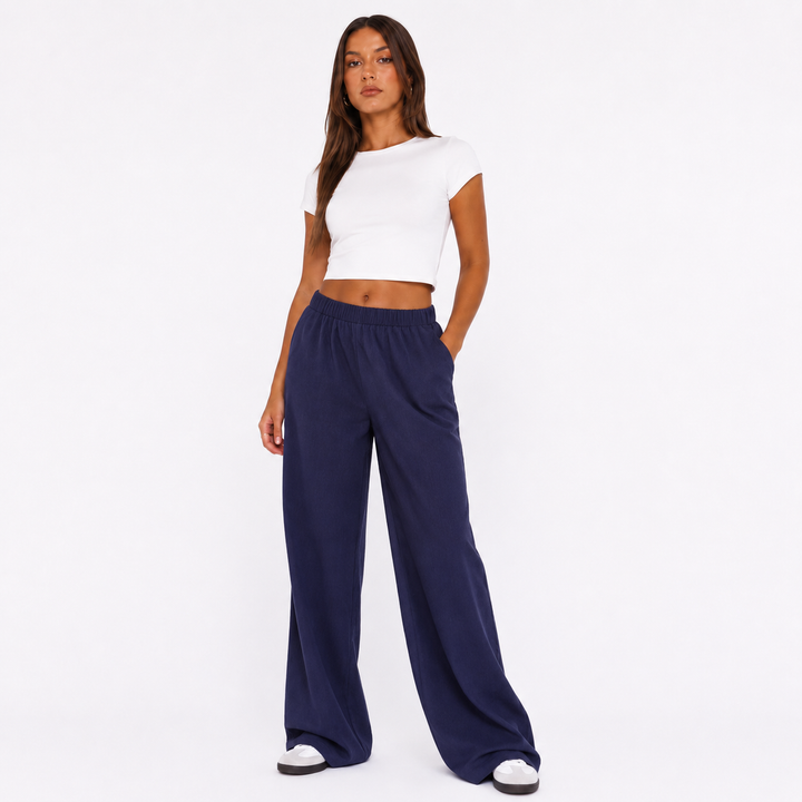 Dark blue wide leg pants for women on a studio model, showing elastic waist, clean leg line and relaxed full-length silhouette.
