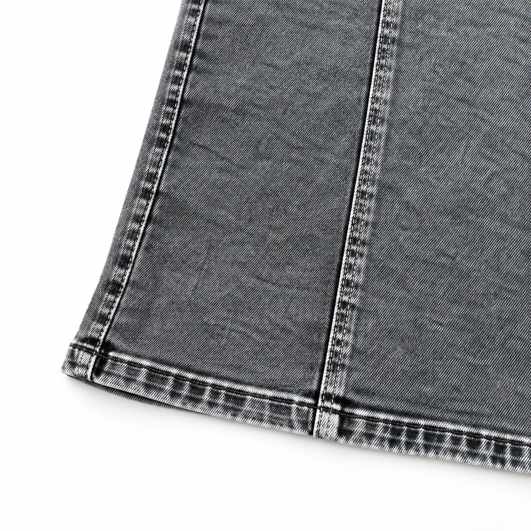 Close-up of the Black Grey dress laid flat on white, showing washed denim, the lower seam and stitched hem without any model.