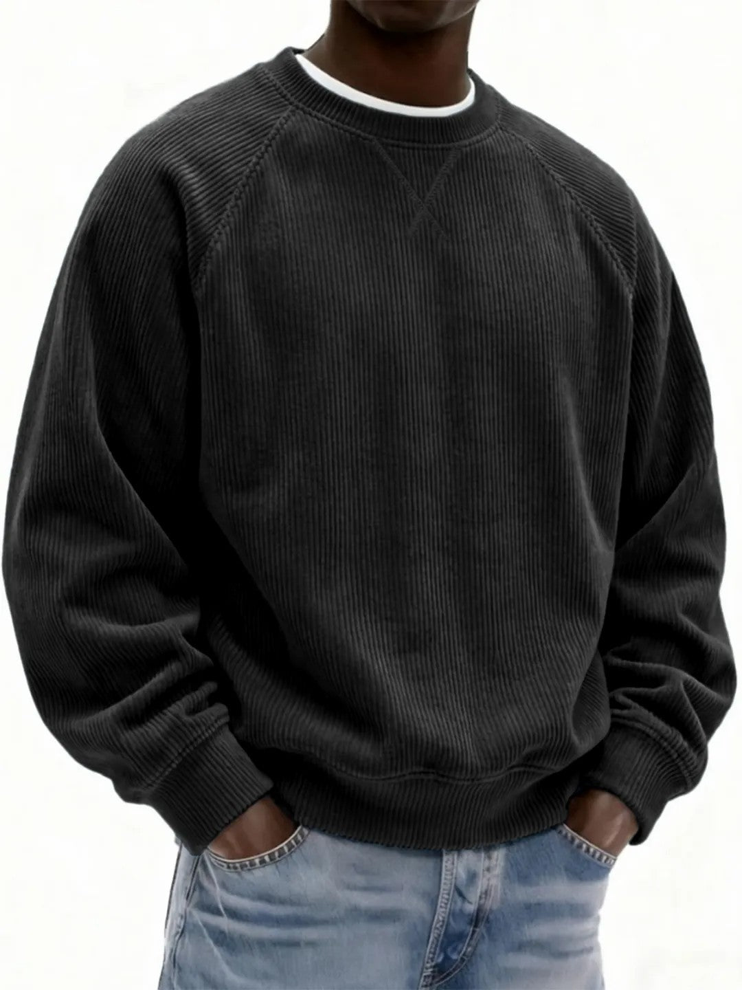 Person wearing a black corduroy sweatshirt and light blue jeans on a white background